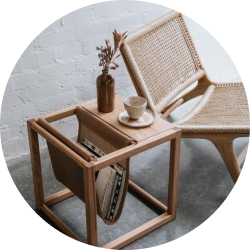 Modern wooden side table with magazine holder and woven chair in minimalist setting