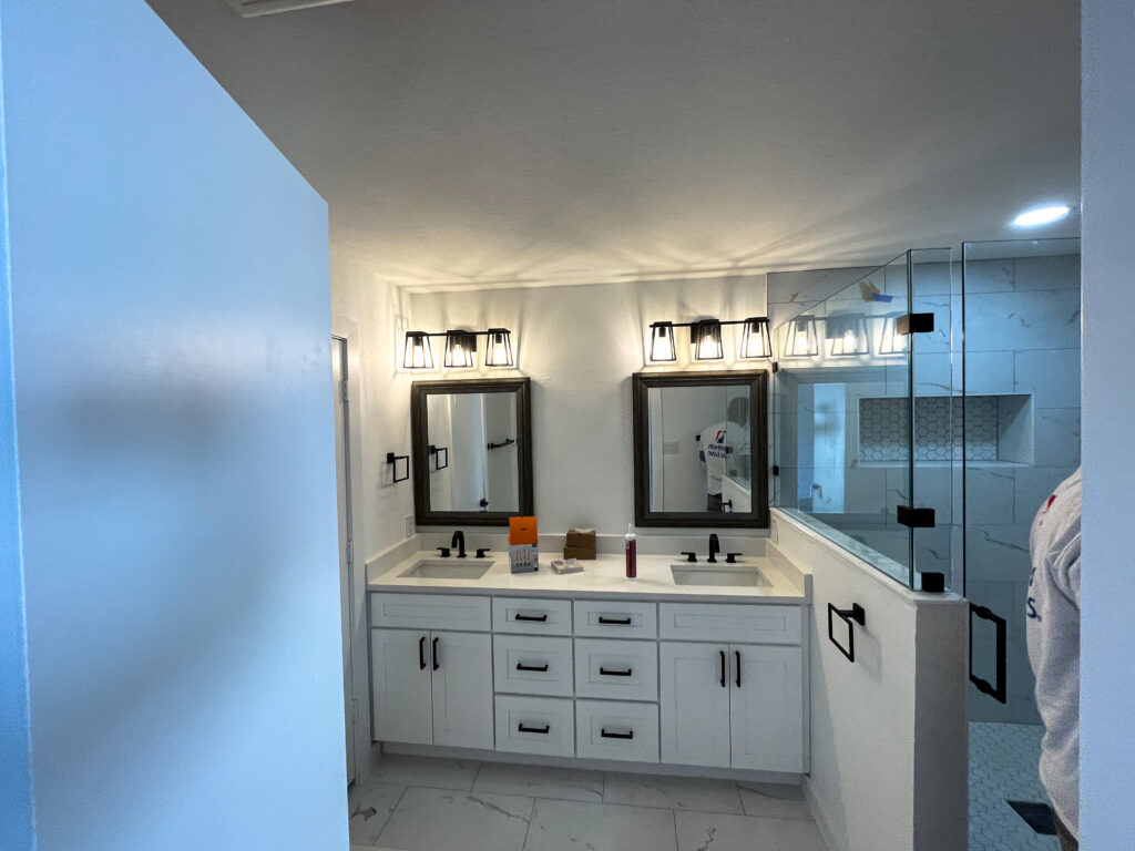 Casabianca Remodeling completed Texas home remodeling services with a fully renovated bathroom featuring new vanities, lighting, and a glass shower enclosure